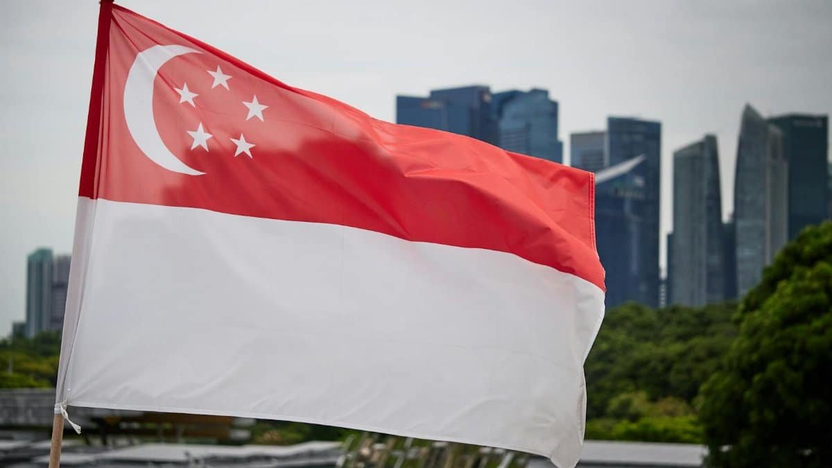 Singapore national flag waving with city skyline backdrop, symbolizing pride and modernity.