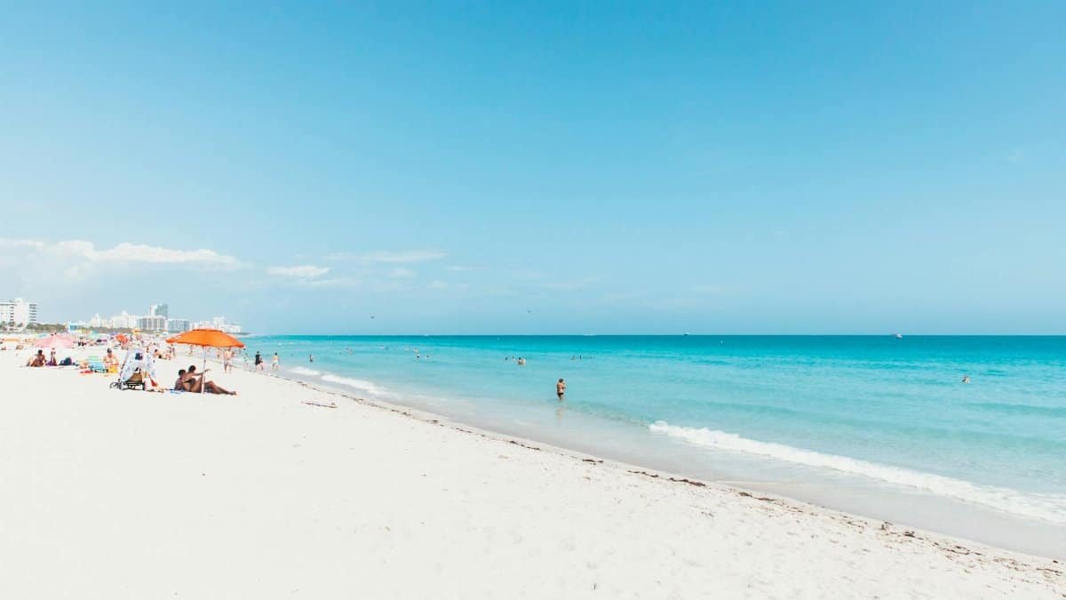 A vibrant Miami Beach scene with clear skies, blue ocean, and white sand.