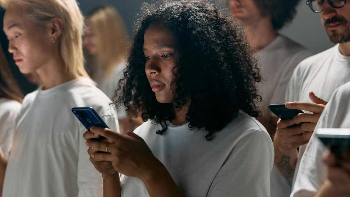 A diverse group of young adults focused on smartphones, symbolizing modern social connections and technology.
