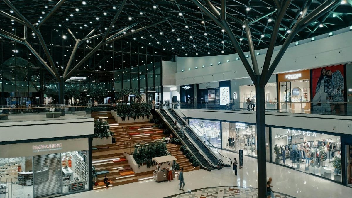 Explore a spacious and contemporary shopping mall featuring trendy shops, lush greenery, and stylish architecture.