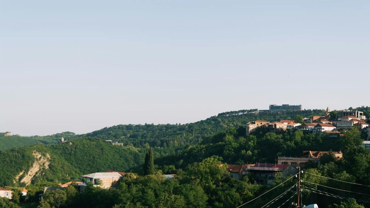 Beautiful rural mountain village surrounded by lush greenery and hills under a clear sky.