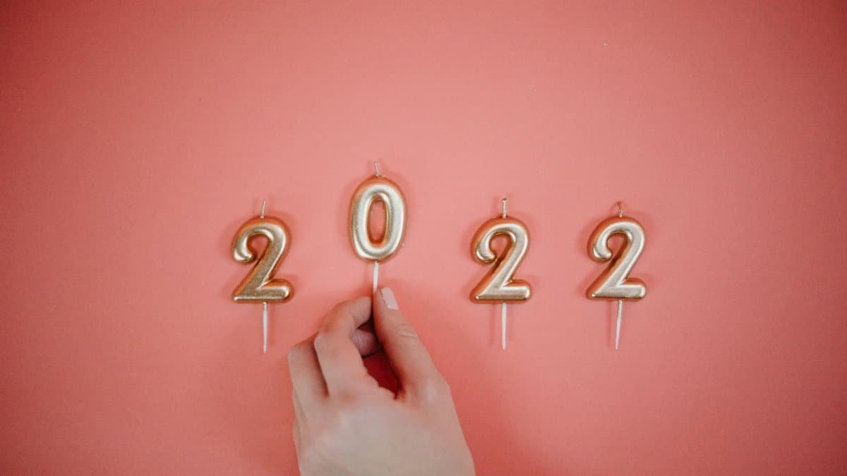 Celebrate the New Year 2022 with golden number candles on a pink backdrop.