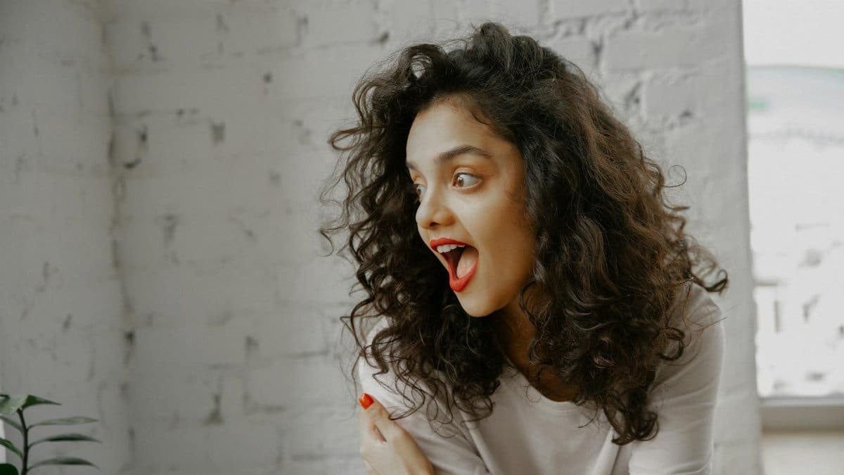 Portrait of an excited woman expressing surprise in a bright indoor space.