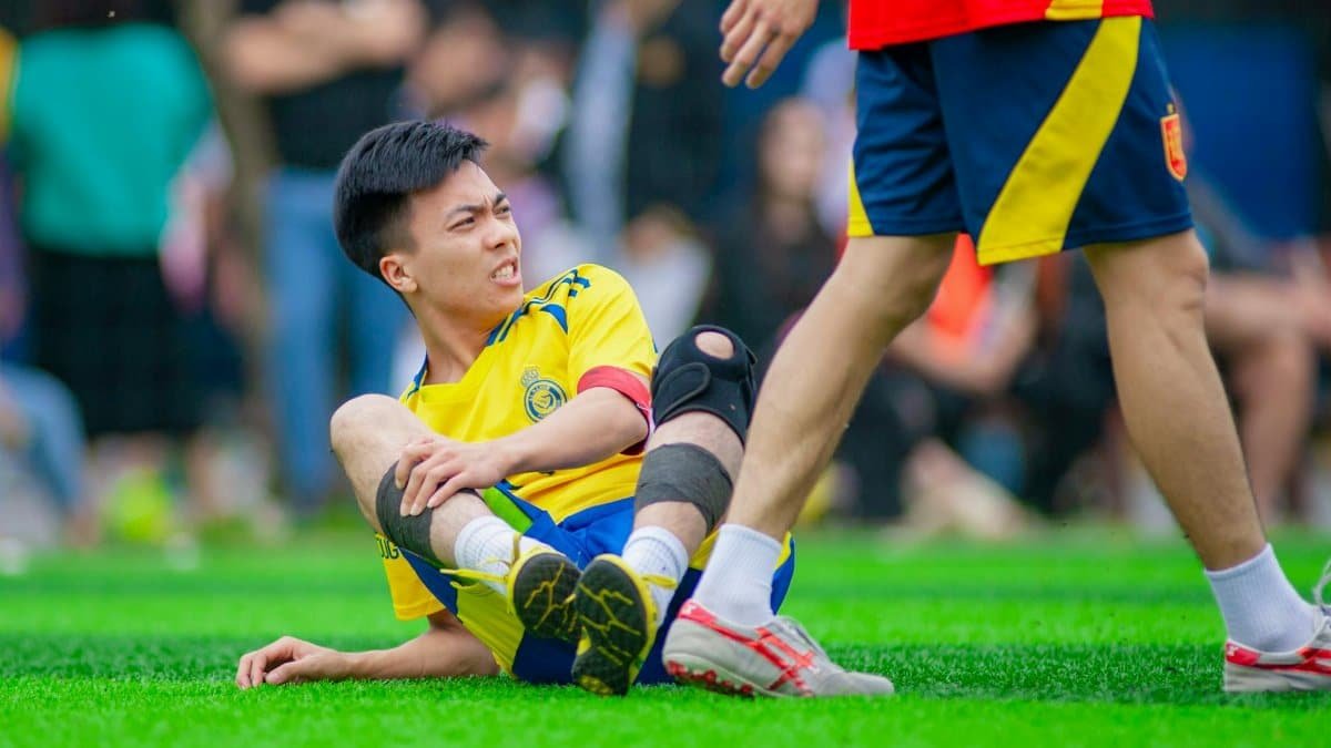 Soccer player on ground with knee injury during match.