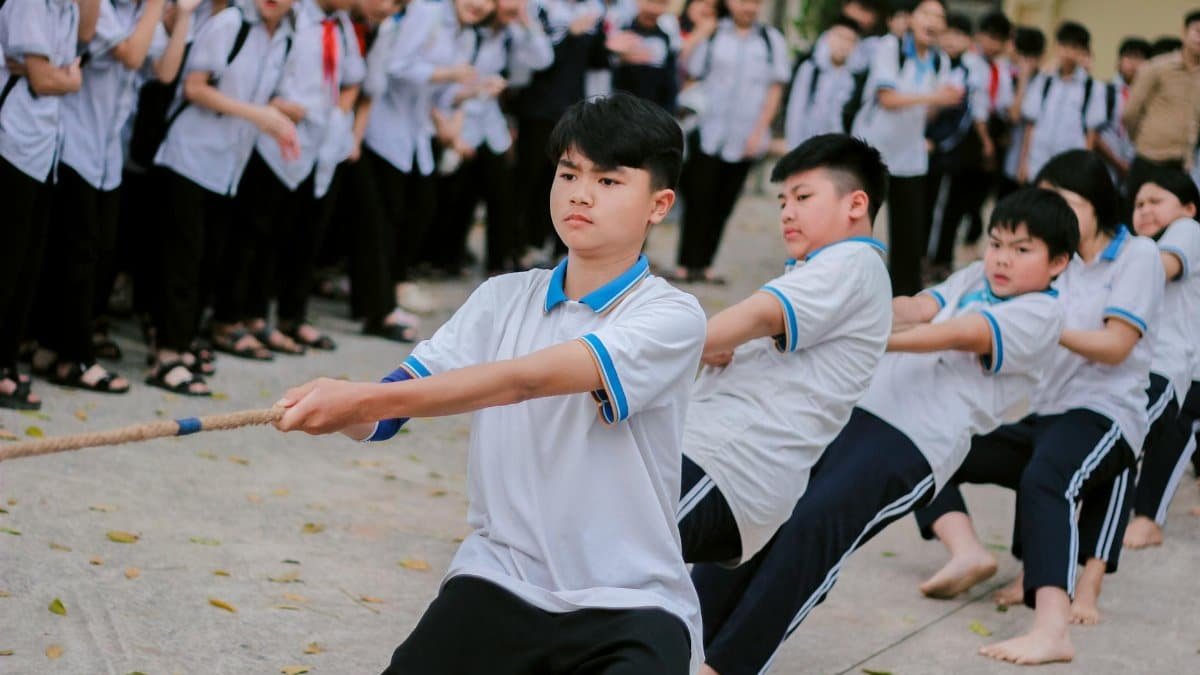 Group of students participating in a competitive outdoor tug-of-war game.