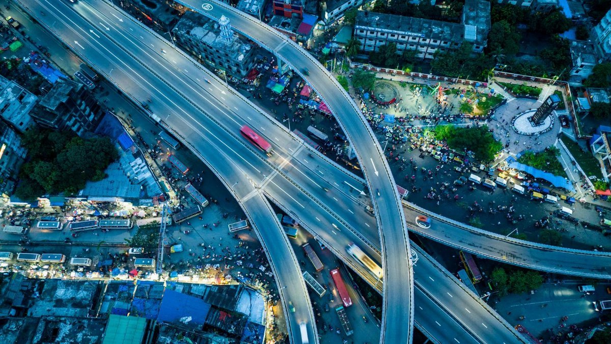 A vibrant aerial view of a busy urban highway interchange illuminated at night.