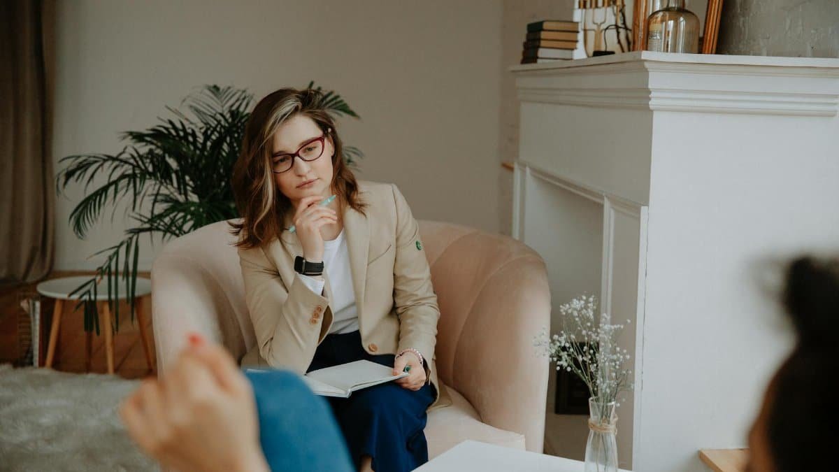 A thoughtful female therapist engages in a counseling session indoors, promoting mental well-being.