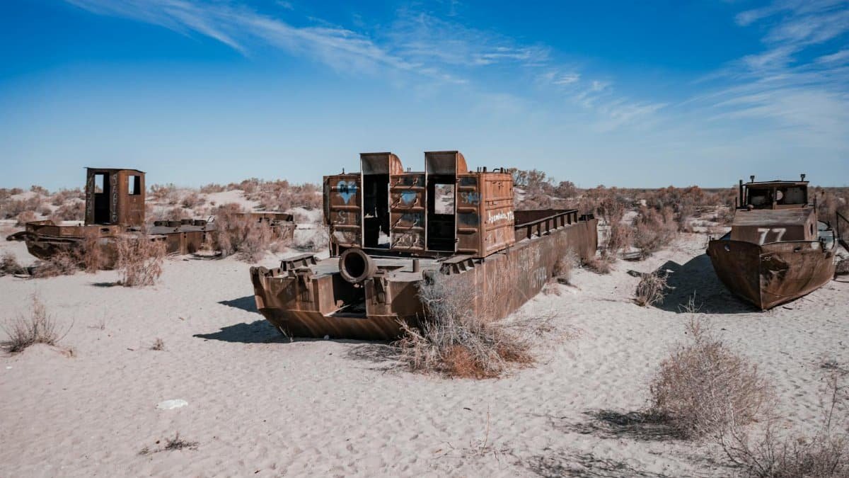 Rusty ships abandoned in the Aral Sea desert, highlighting environmental disaster impacts.