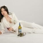 Stylish asian woman posing with wine bottles on white background in Hà Nội.