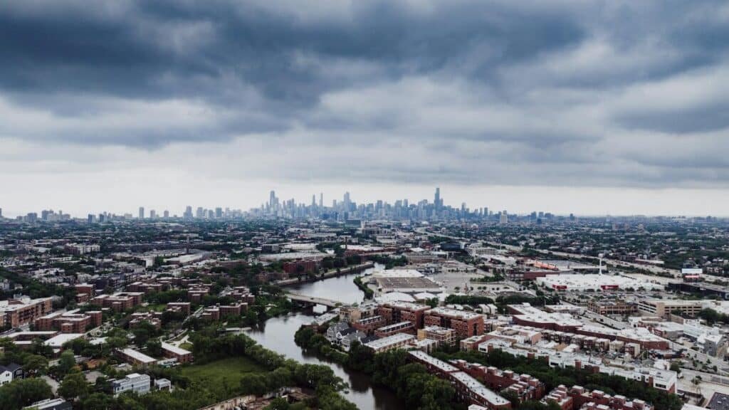 Stunning aerial view of Chicago skyline with dramatic clouds and river foreground.