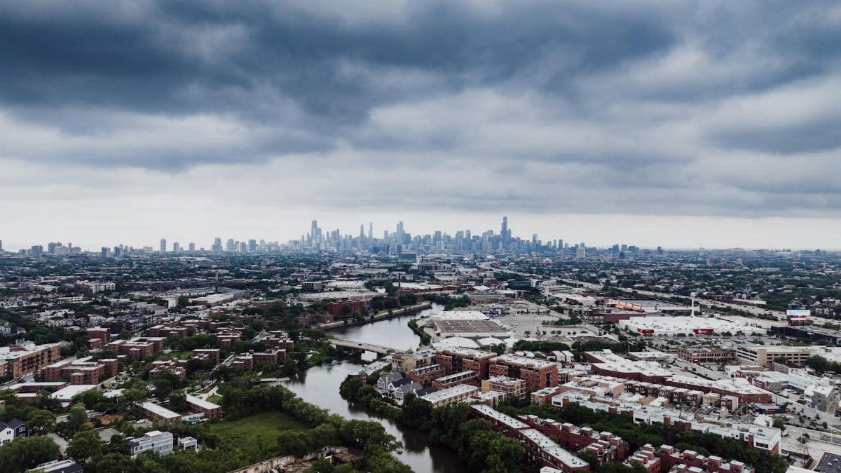 Stunning aerial view of Chicago skyline with dramatic clouds and river foreground.