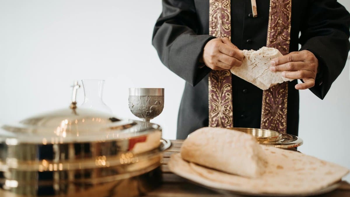 A priest breaking bread during a Holy Communion service, symbolizing a Christian religious ritual.