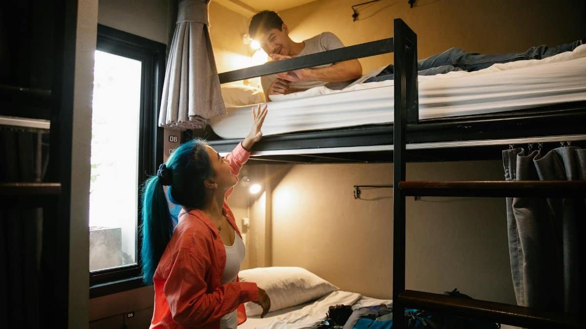Young couple enjoying a cozy stay in a hostel bunk bed room, perfect for budget travel and bonding.