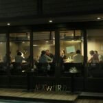 A view of people enjoying a relaxed gathering inside a modern coffee shop with wooden decor.