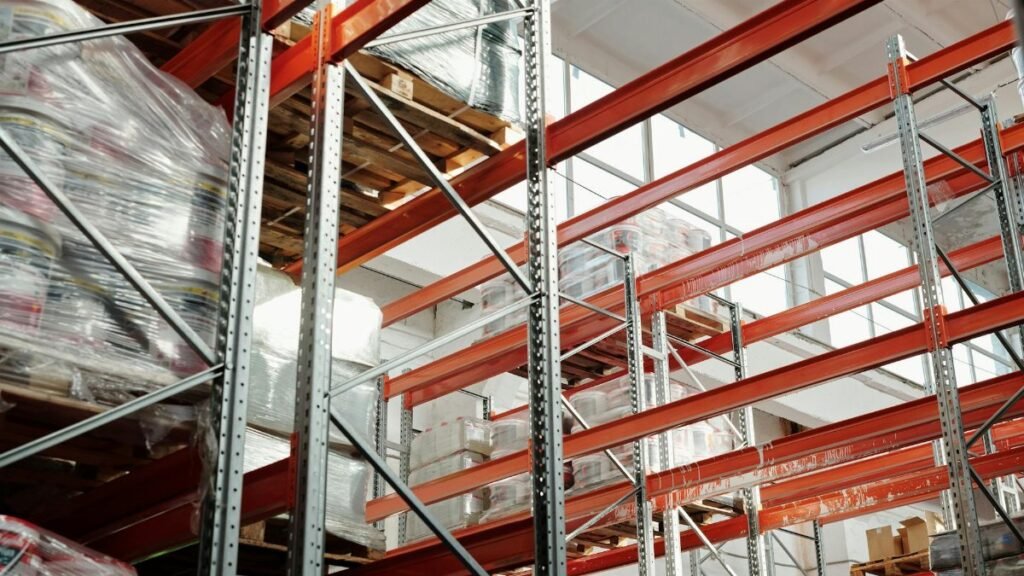 Bright modern warehouse featuring pallets and storage racks for logistics and inventory management.