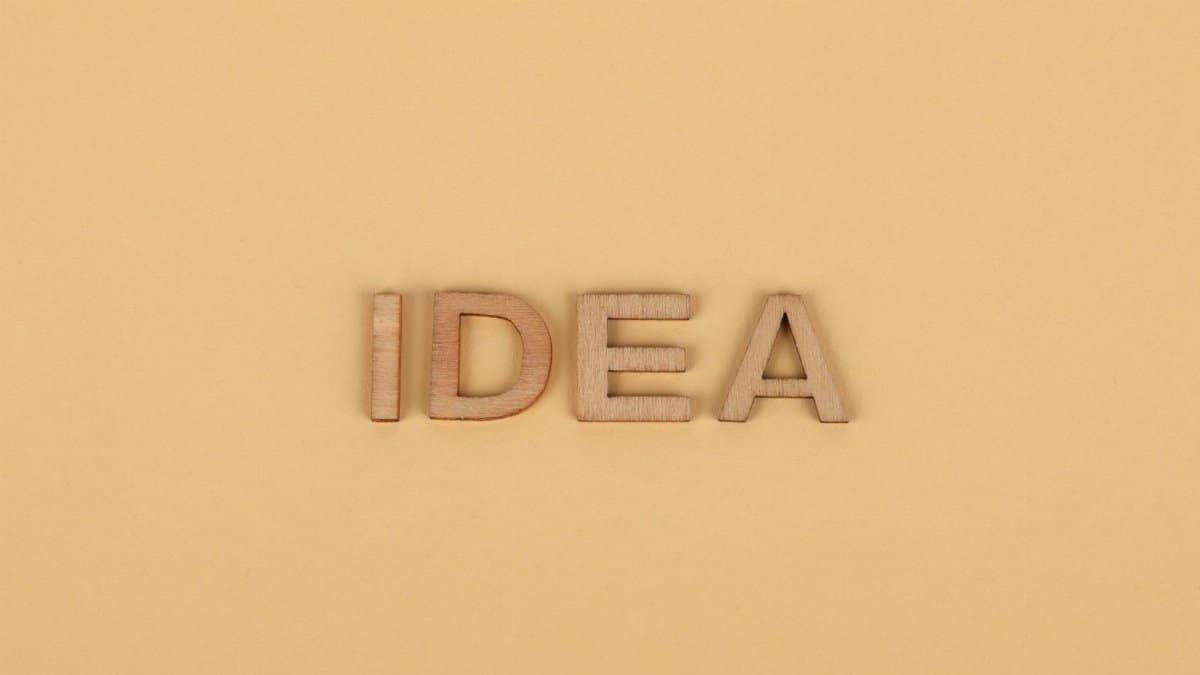 Wooden letters forming 'IDEA' on a plain beige surface, representing creativity.
