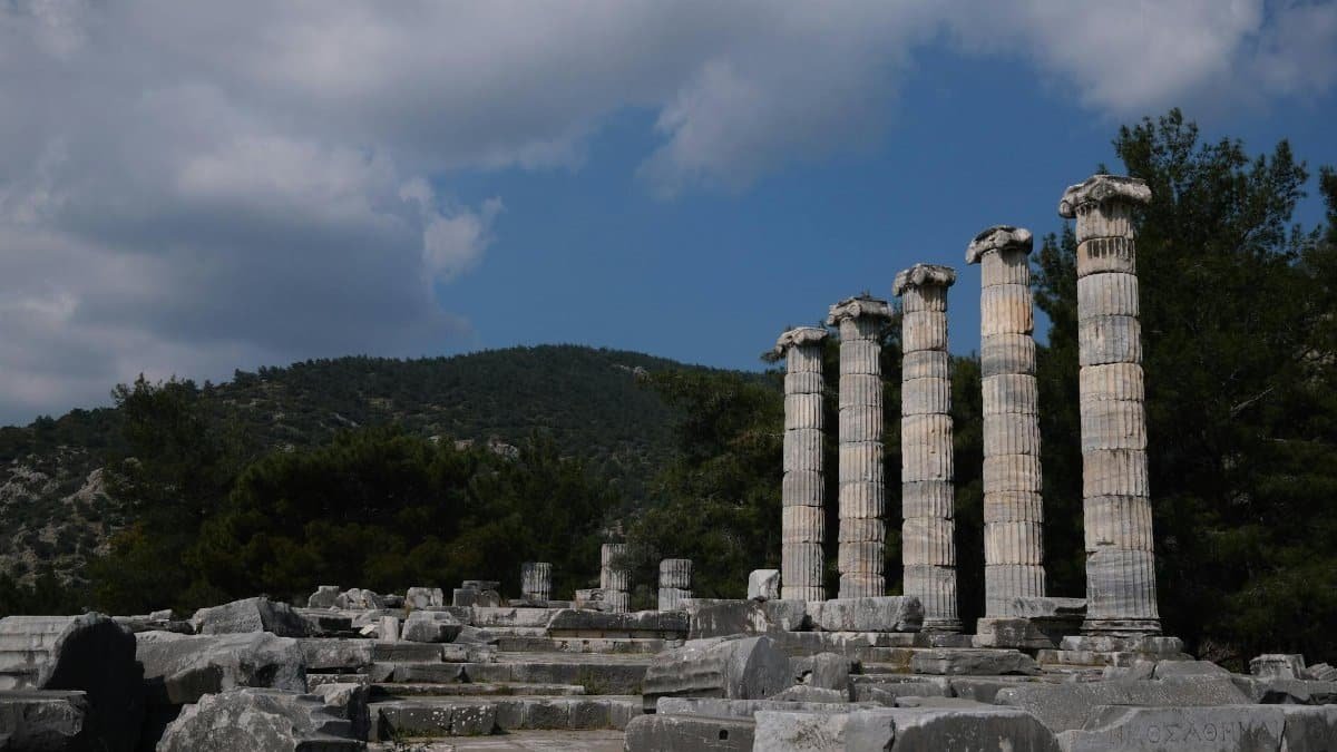 Stone columns of an ancient Greek temple in Aydın, Türkiye under a bright blue sky.