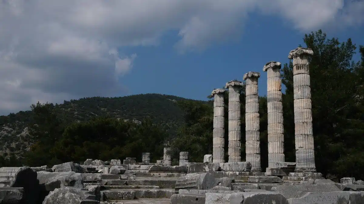 Stone columns of an ancient Greek temple in Aydın, Türkiye under a bright blue sky.