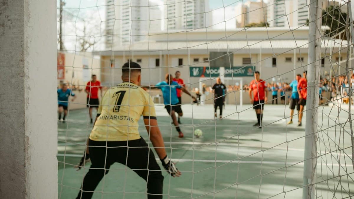 Goalkeeper prepares to defend during an indoor soccer game. Action-packed sports moment.