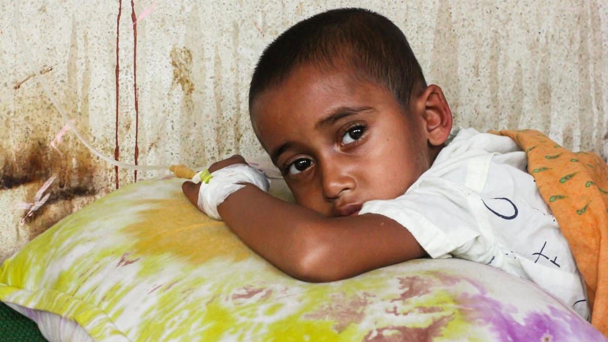 Young child resting with IV in hospital setting, showing concern.