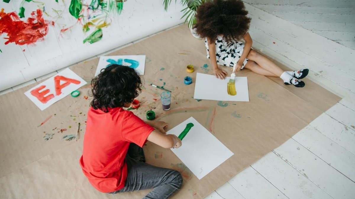 Two children painting together indoors, expressing creativity and joy through art.