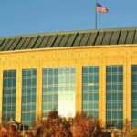 Aurora Municipal Center building with waving American flag in daylight.