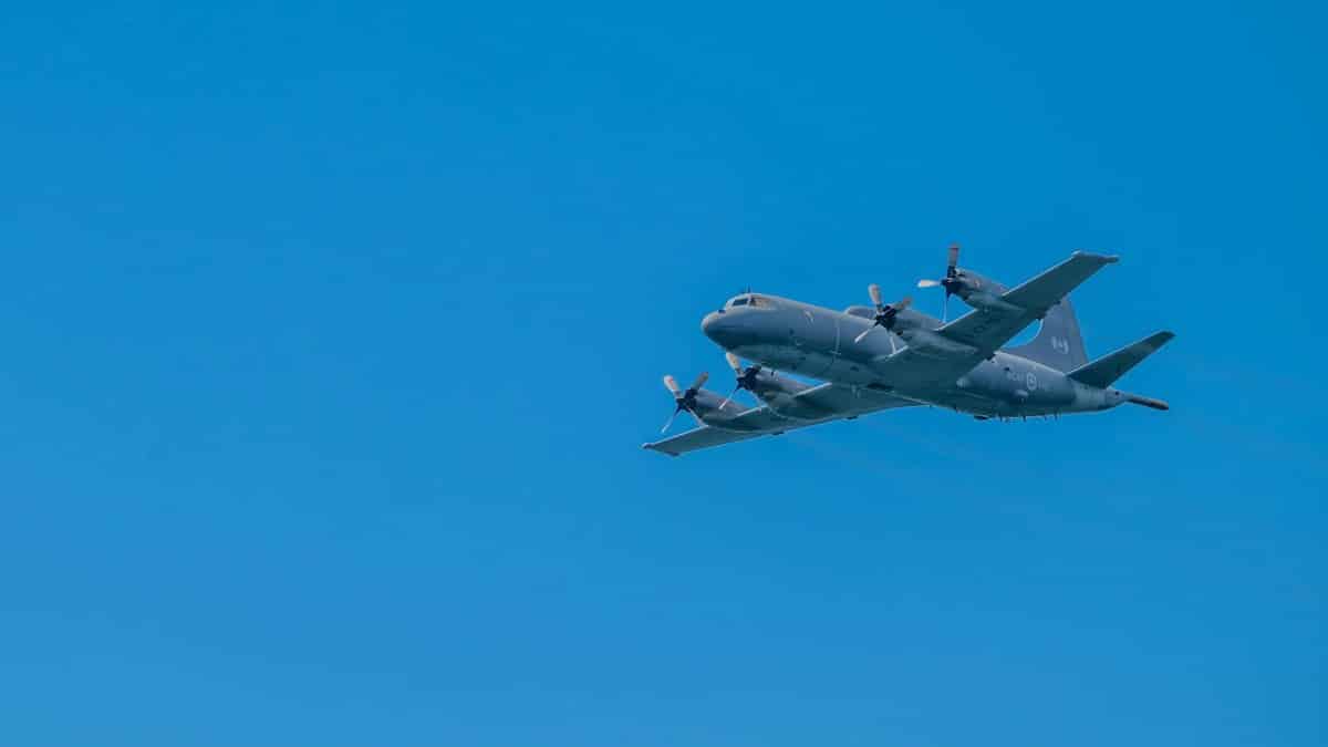 Propeller military aircraft soaring against a bright blue sky, showcasing aviation technology.