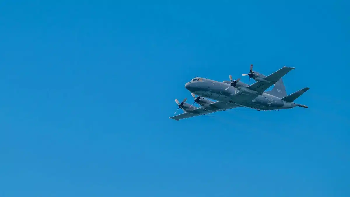 Propeller military aircraft soaring against a bright blue sky, showcasing aviation technology.