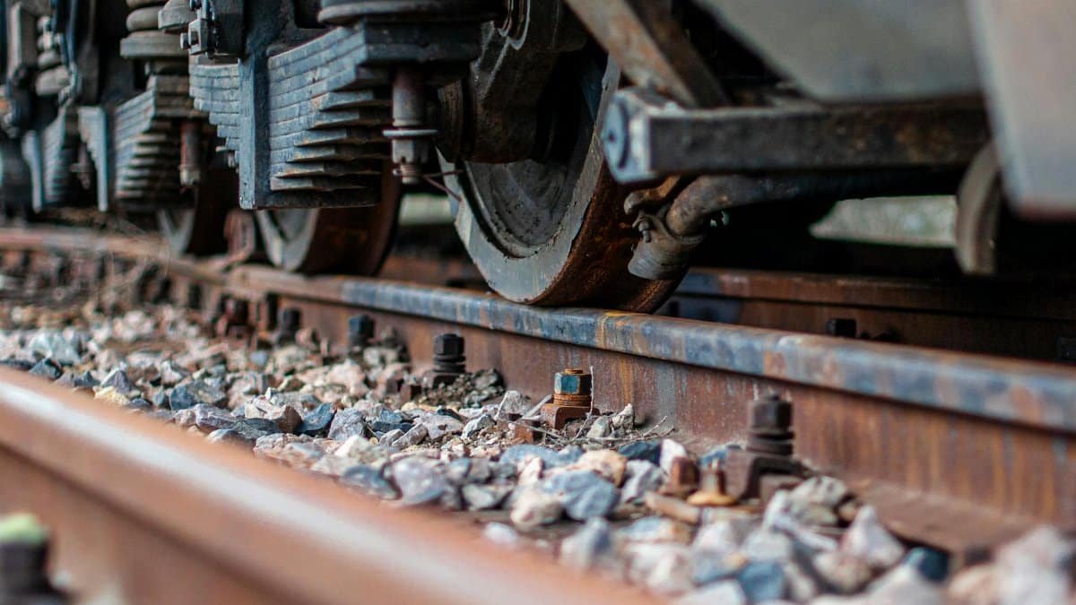 Detailed view of train wheels and rusty railway tracks with nuts and bolts.