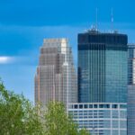 Stunning view of Minneapolis skyscrapers framed by lush greenery under a clear blue sky.