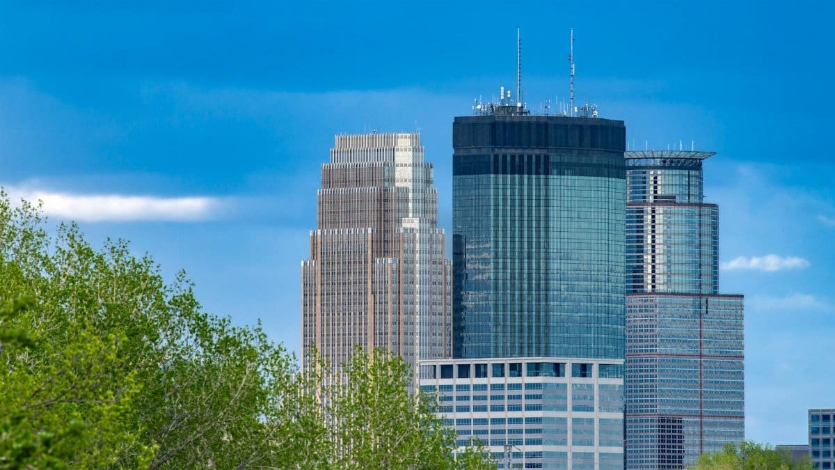 Stunning view of Minneapolis skyscrapers framed by lush greenery under a clear blue sky.