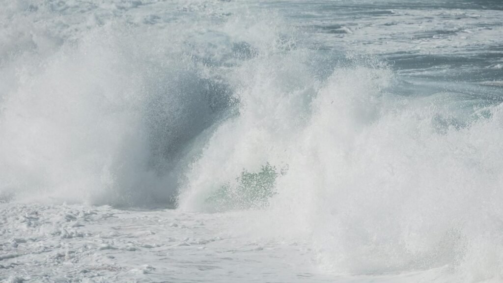 Powerful ocean waves crashing against the shore, creating a turbulent and foamy scene.