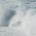Powerful ocean waves crashing against the shore, creating a turbulent and foamy scene.