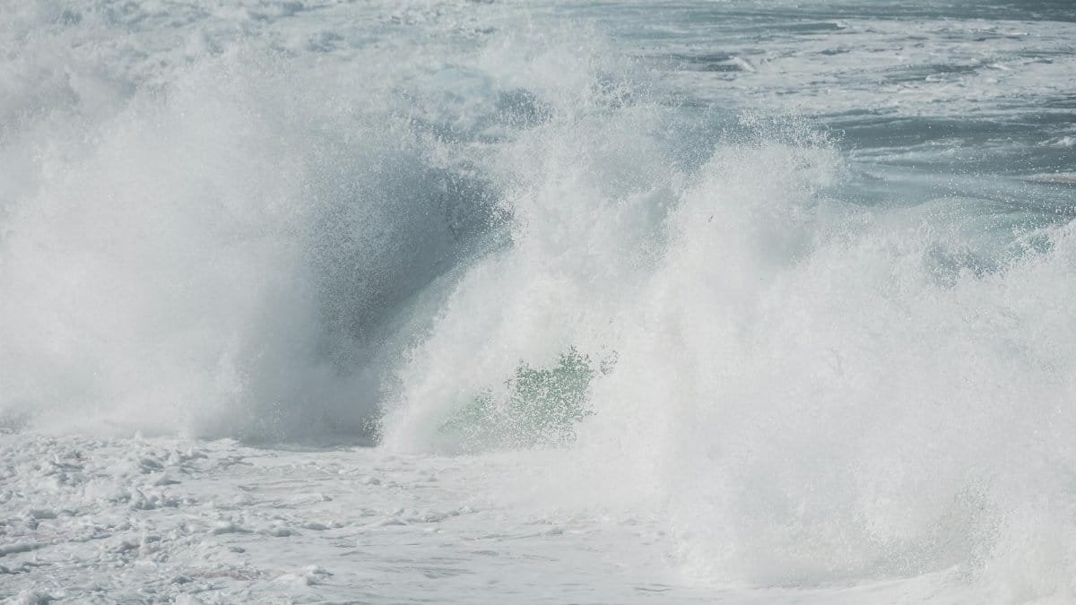 Powerful ocean waves crashing against the shore, creating a turbulent and foamy scene.