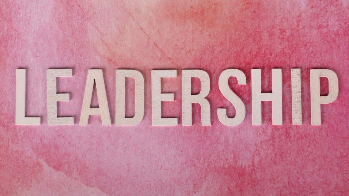 Inspirational leadership text on a vibrant pink watercolor background.