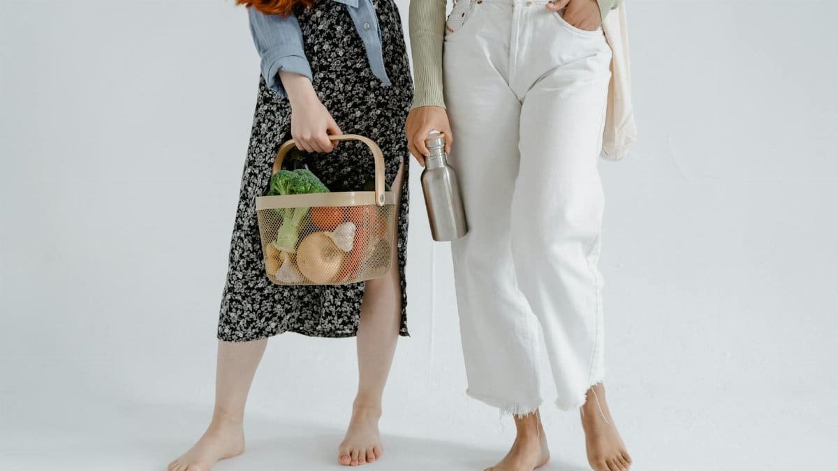 Two women holding reusable items, promoting sustainable living.