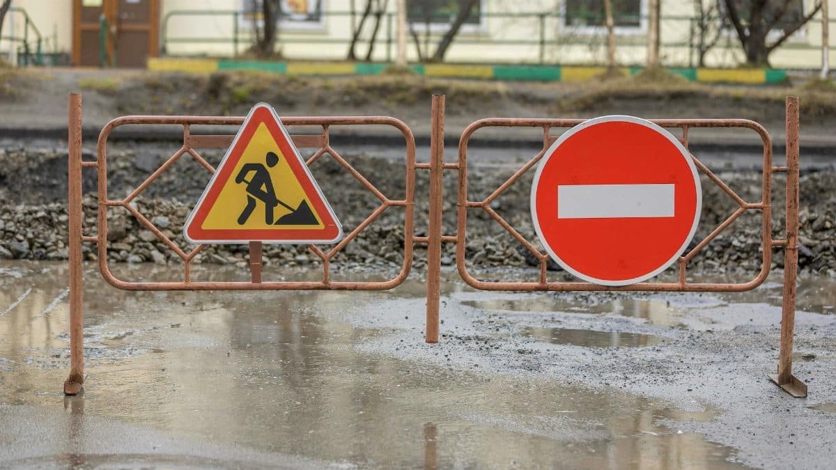 Close-up of construction signs and barriers in a muddy area outdoors, indicating no entry.