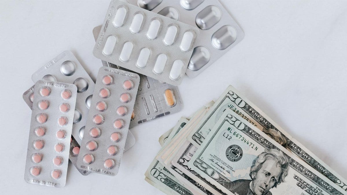 Top view of different blisters of medications and pills composed with heap of paper money