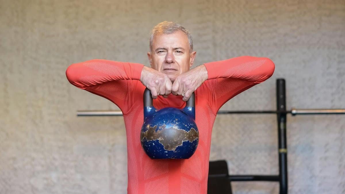 Elderly man engages in strength training with kettlebell, promoting fitness and healthy aging.