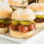 Tasty Texas-style BBQ beef sliders topped with pickles and onions, perfect for parties.