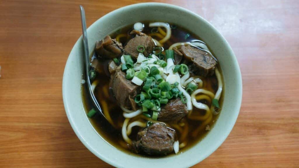 Savor the flavors of authentic Taiwanese beef noodle soup garnished with green onions.