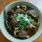 Savor the flavors of authentic Taiwanese beef noodle soup garnished with green onions.