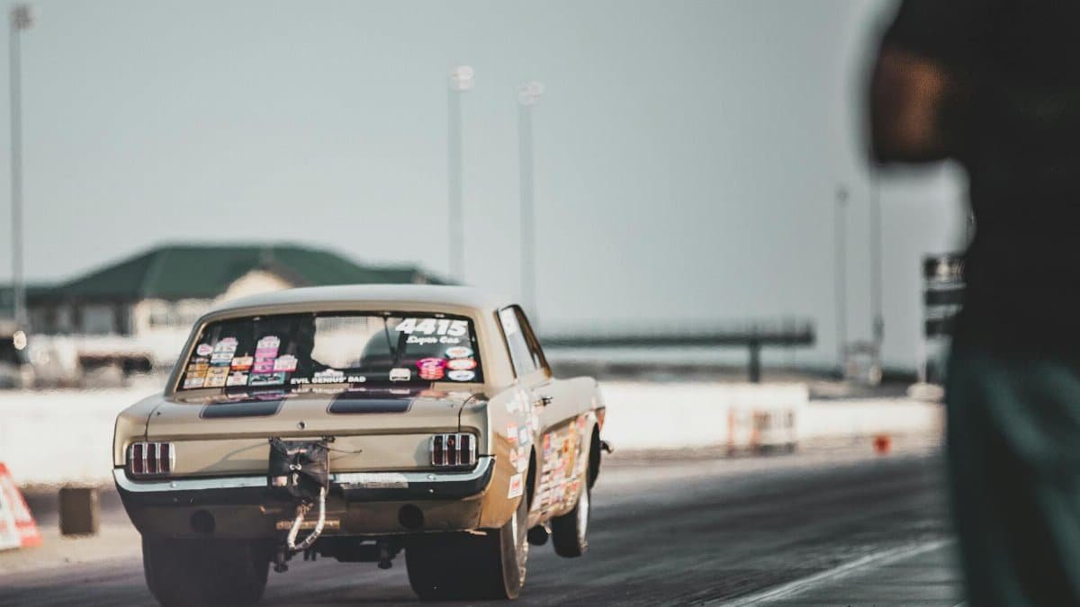 A racing car accelerates on a Topeka race track under clear skies.