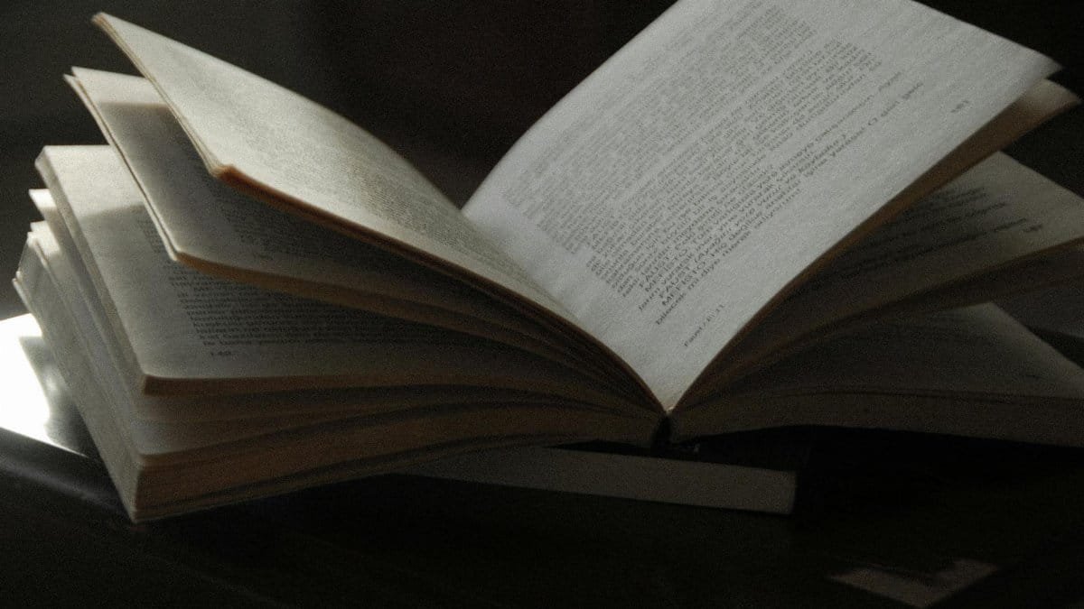 A close-up of an open book with visible text, placed on a dark wooden surface. Ideal for reading-themed content.