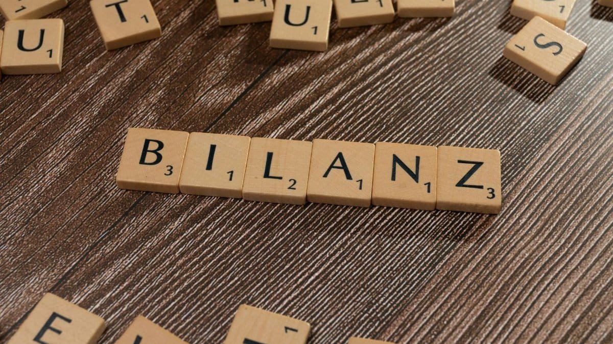 Scrabble tiles spelling 'Bilanz' on a wooden surface, symbolic of financial balance.