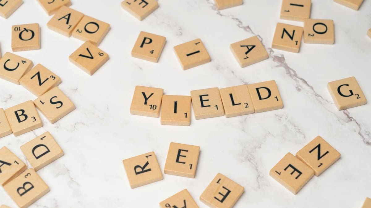 Scrabble tiles forming the word 'YIELD' on a marble surface, symbolizing finance and investment.