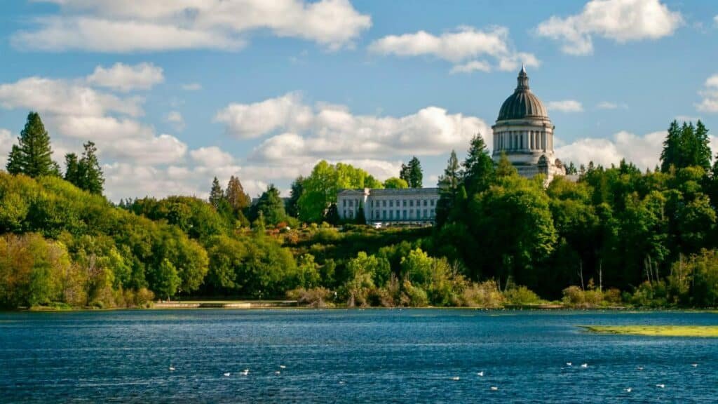 Scenic view of Washington State Capitol and surrounding greenery by the lake in Olympia.