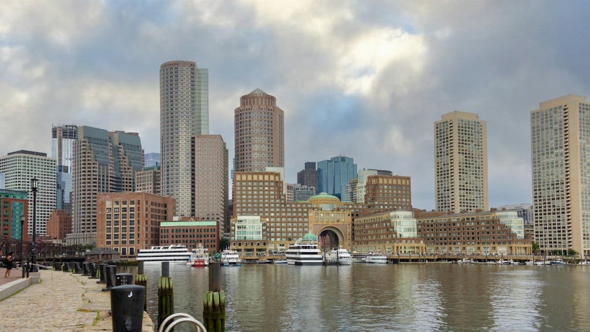 Panoramic view of Boston skyline with modern skyscrapers and harbor reflections, capturing urban architecture.
