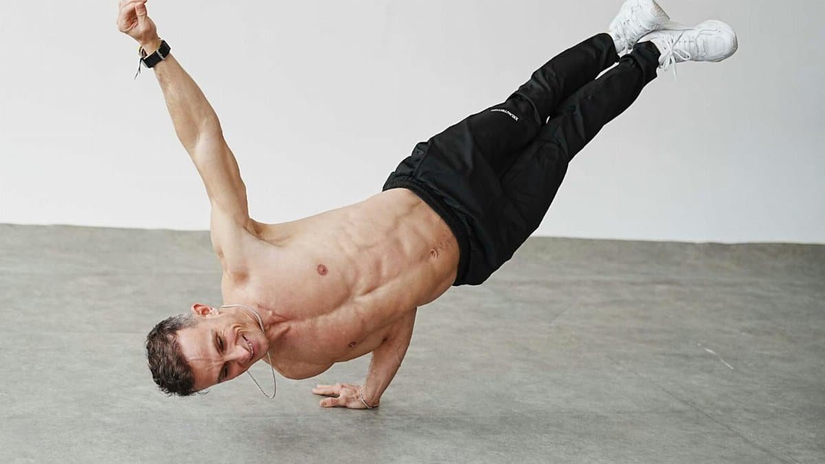 Energetic man performing a one-arm handstand in a Berlin studio. Capturing movement and strength.