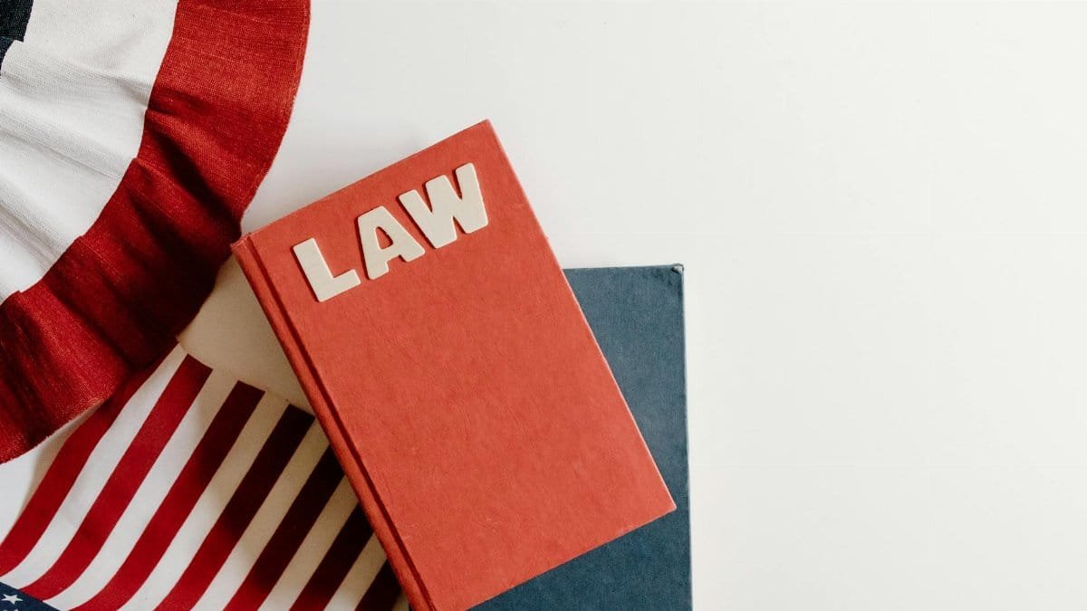 A flat lay of a red law book, American flag, and ribbon displaying patriotic themes.